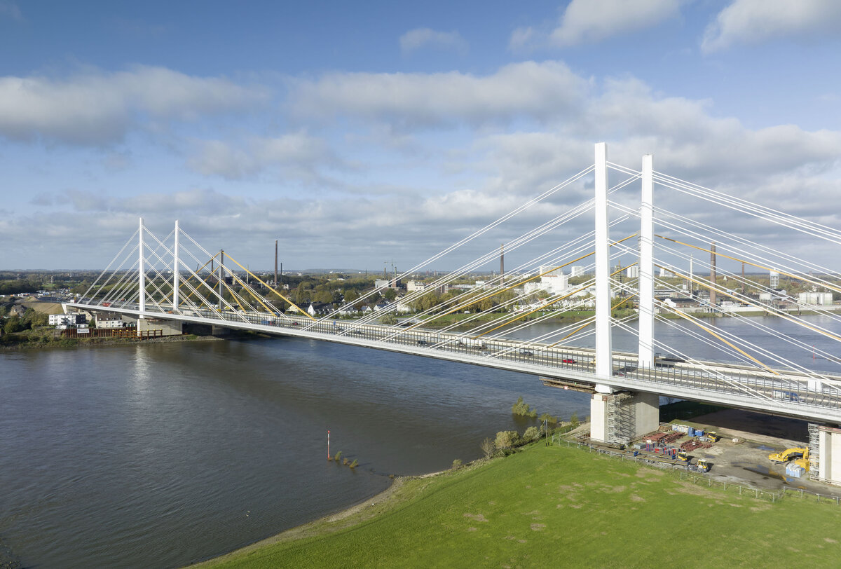 Blick vom Ufer auf das fertiggestellte 1. Teilbauwerk der Rheinbrücke Duisburg-Neuenkamp, im Hintergrund die alte Brücke